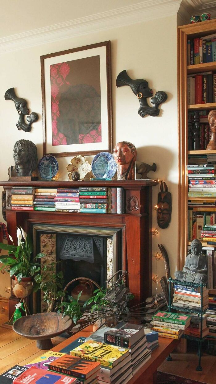 Cozy bold and beautiful interiors featuring eclectic decor, bookshelves, sculptures, and vibrant plants in a warm living space.