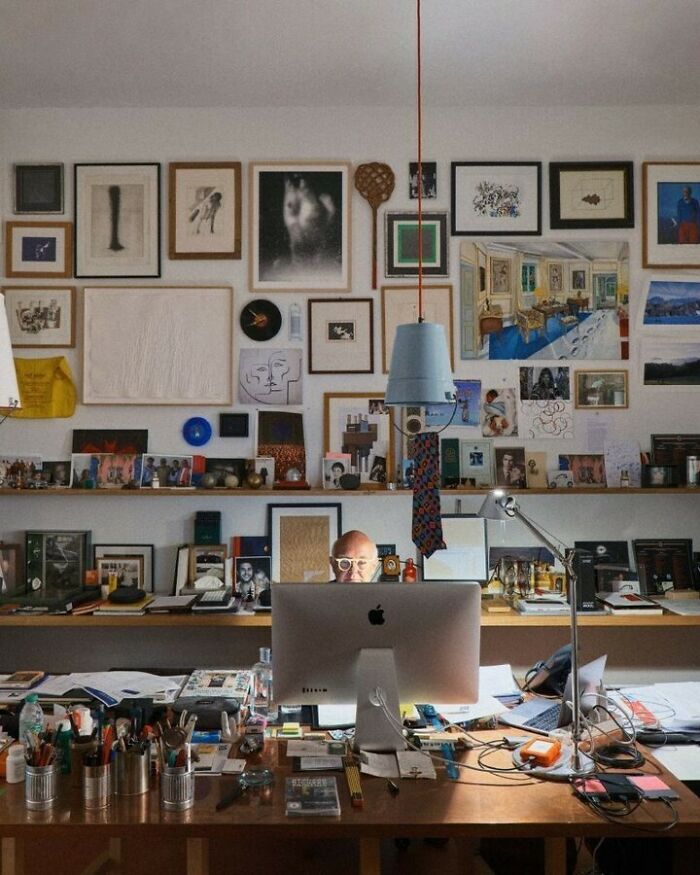 Creative workspace with bold and beautiful interiors featuring art-filled walls and a cluttered wooden desk in a vibrant room.