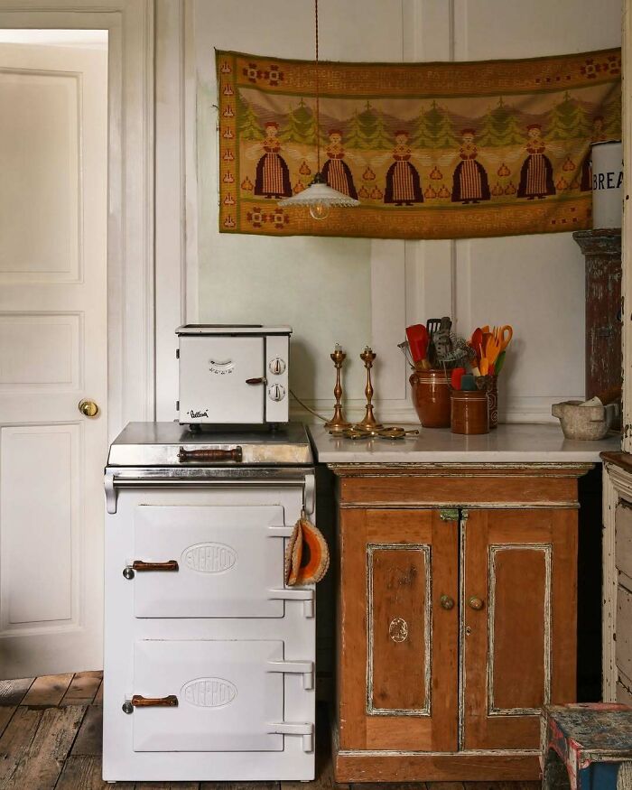 Vintage kitchen interior with bold and beautiful rustic stove, wooden cabinets, and colorful cookware accents.