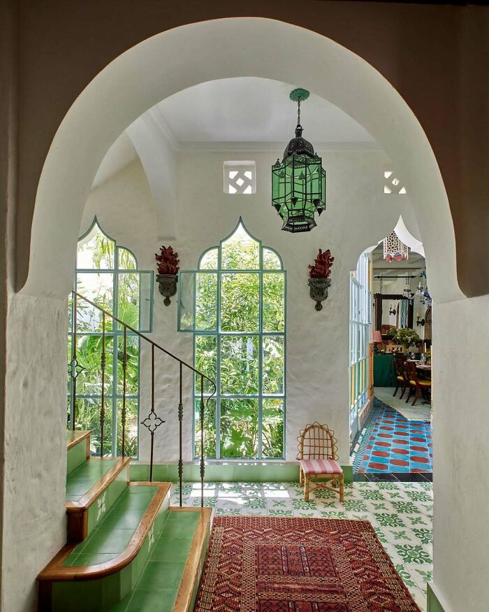 Bold and beautiful interiors featuring vibrant green tiles, arched windows, and unique decorative lighting in a bright living space.