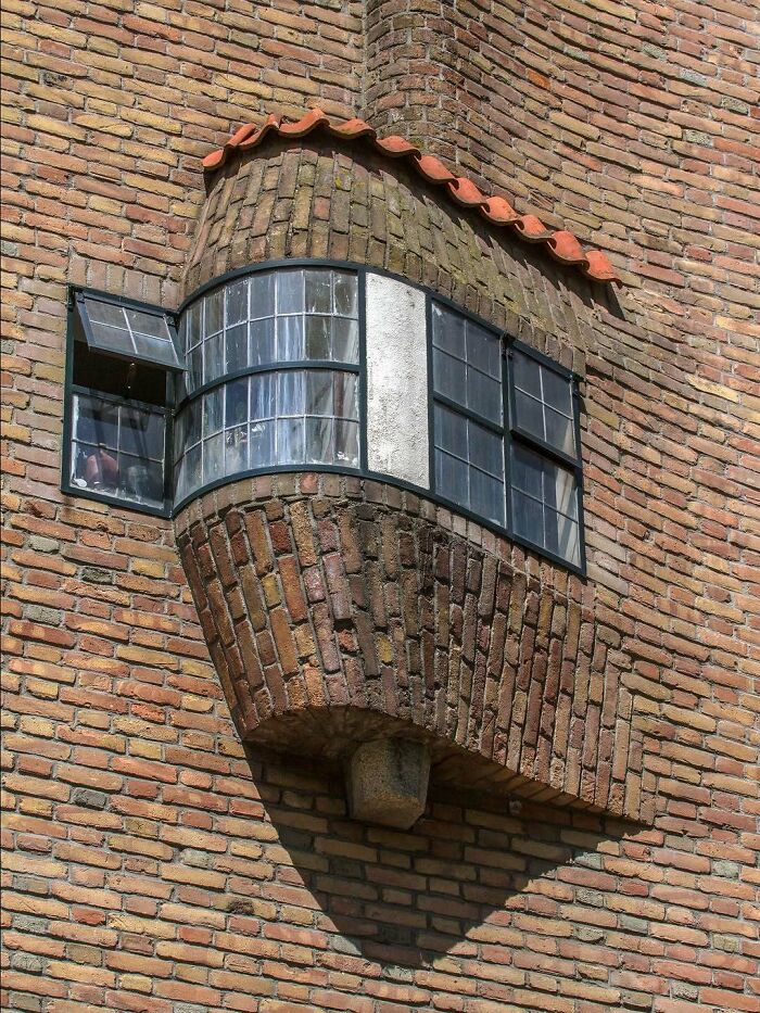 Curved brick architectural structure with multi-pane windows showcasing creative architectural design details.