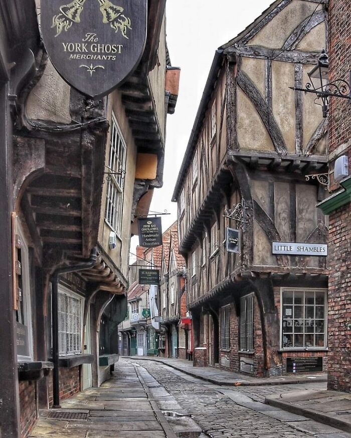 Narrow street lined with medieval timber-framed architectural structures showcasing historic design and creativity.