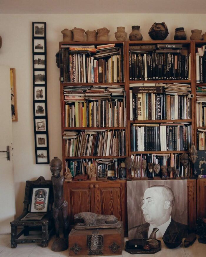 Cozy living room with bold and beautiful interiors featuring wooden bookshelves, art pieces, and eclectic decor elements.