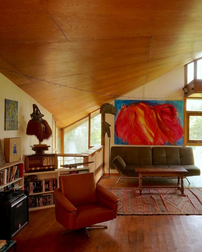 Bold and beautiful interiors with wooden ceilings, eclectic art, vintage furniture, and warm natural lighting in a cozy living space