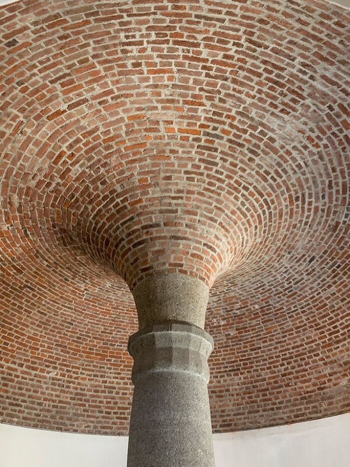 Intricate brick architectural structure with a stone column supporting a unique curved dome ceiling design.