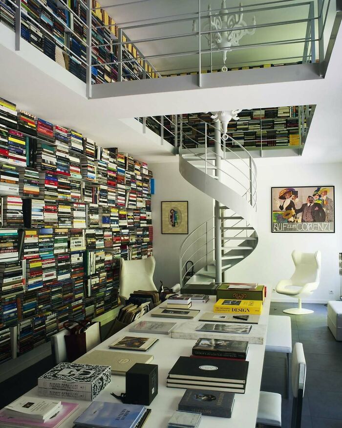 Modern interior with a spiral staircase and wall covered in books showcasing bold and beautiful interiors design.