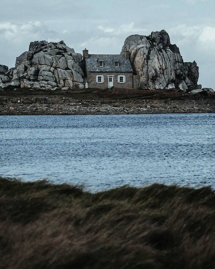 Stone house built between massive rock formations by the sea, showcasing beautiful and amazing architectural structures.