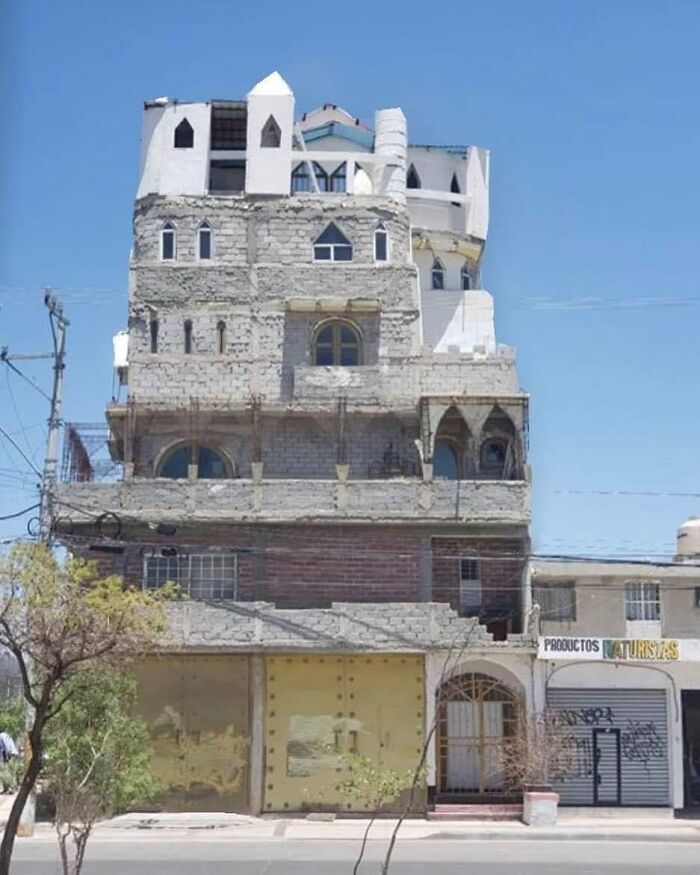 Unfinished ugly building with rough concrete facade and castle-like features in an urban setting, an architectural malpractice example.