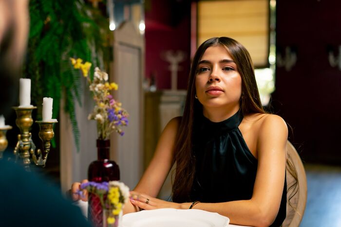 Young woman on a first date showing signs of discomfort and red flags in a dimly lit restaurant setting.