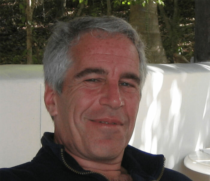 Middle-aged man with gray hair smiling slightly, in an outdoor setting with trees and white furniture, related to prison details. Middle-aged man with gray hair smiling slightly, in an outdoor setting with trees and white furniture, related to prison details.