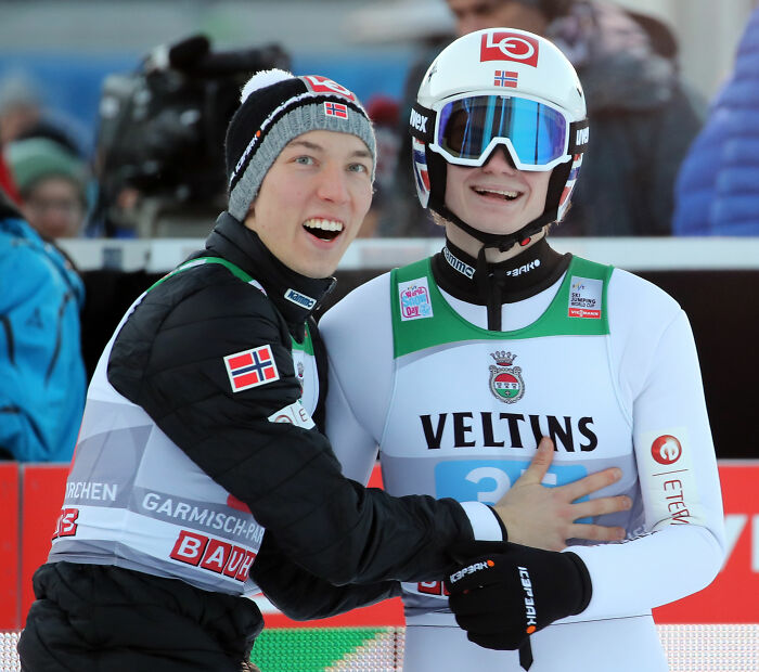 Two Winter Olympics athletes in ski gear celebrating, highlighting manhood scandal and rule changes in the games.