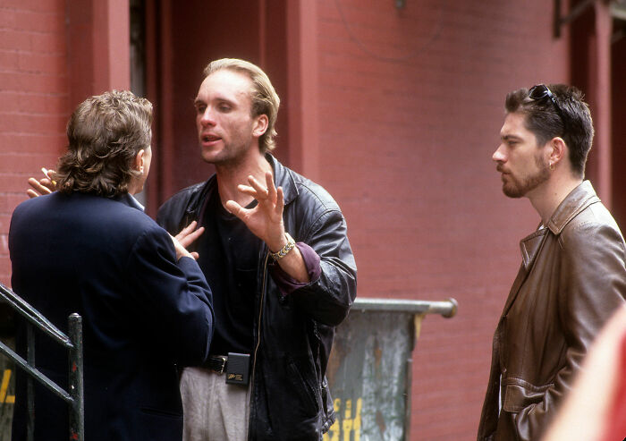 Three men in leather jackets having a serious discussion outdoors, reflecting on Peter Greene's cause of passing confusion.