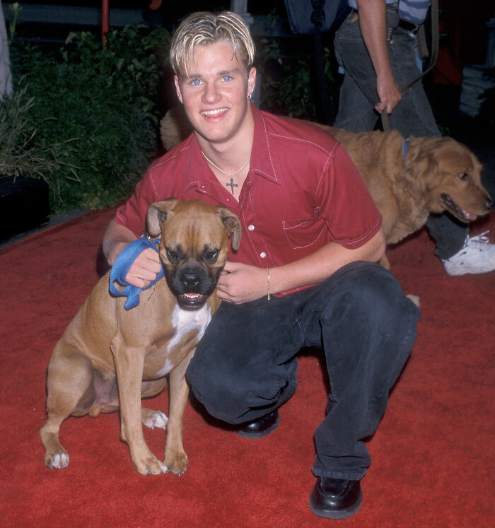 Young Zachery Ty Bryan from Home Improvement smiling and posing with a dog on a red carpet event outdoors.