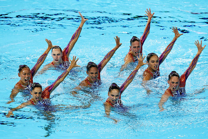 A synchronized swimming team performing a routine in the pool, showcasing Olympic sports summer competition.
