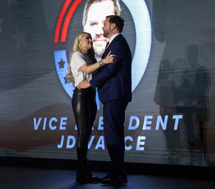 Erika Kirk embracing husband Charlie in front of a large display as TSUPA responds to office change backlash.