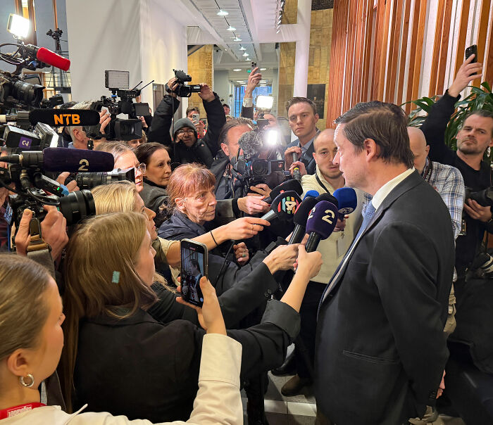 Journalists interview Norway's Crown Princess son in courtroom hallway amid coverage of horrific crimes video evidence.