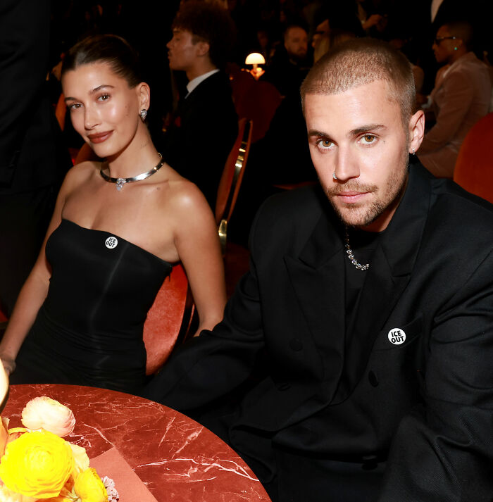 Justin Bieber and Hailey sitting at a table during the Grammys event, dressed in black attire.