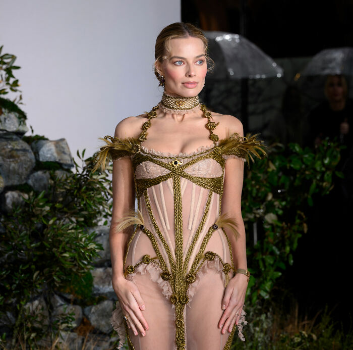 Margot Robbie wearing an intricate gown at an event, related to a male actor's gift sparking women's collective fury.