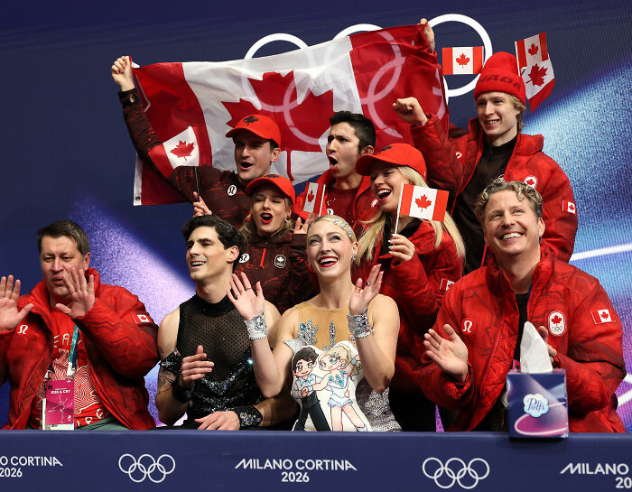 Canadian Olympic ice skater and team celebrating after a routine save following a wardrobe malfunction.