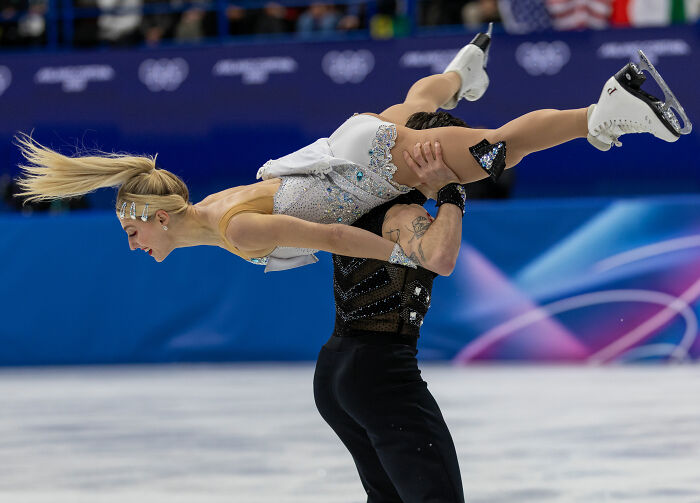 Olympic ice skater performing an incredible save during a routine after a wardrobe malfunction on the ice rink.