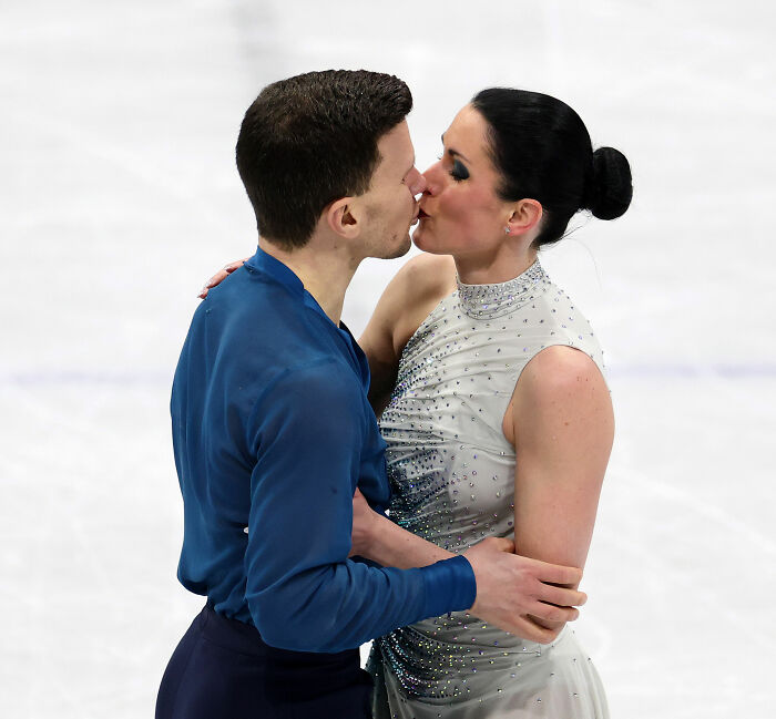 Olympian figure skaters sharing a kiss on ice after stunning admission amid judge's conspicuous scores and cheating accusations.
