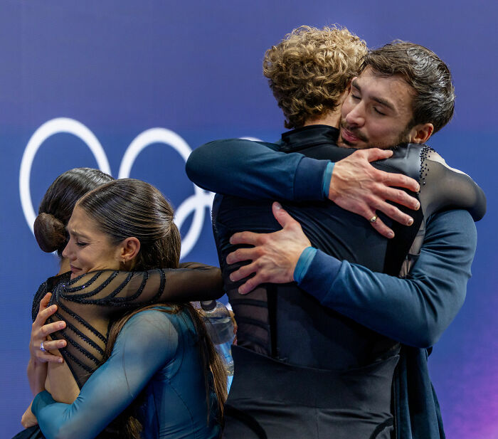 US figure skating team members embracing each other emotionally after a controversial cheating scandal at a major competition.