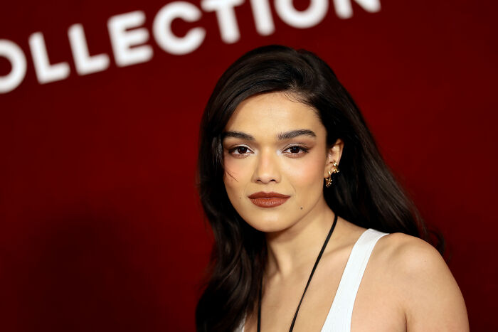 Actress with dark hair and bold makeup posing against a red backdrop amid Scooby Doo fans rallying behind controversial Velma pick.
