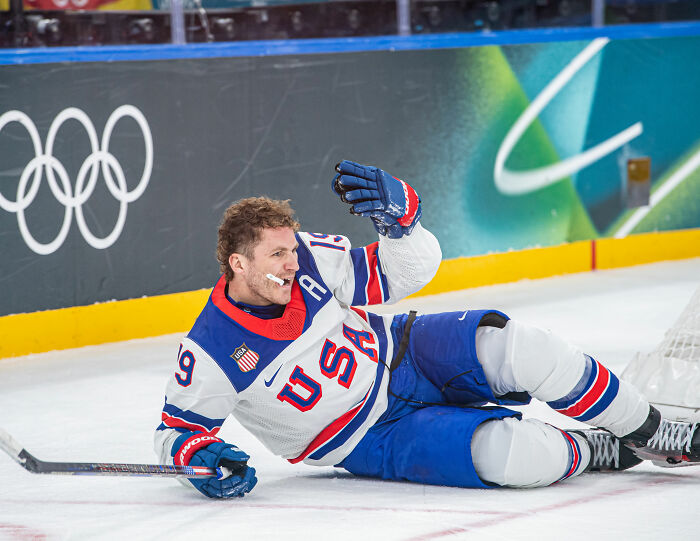 Olympic hockey player in USA jersey on the ice during a heated rivalry moment at the Winter Games.