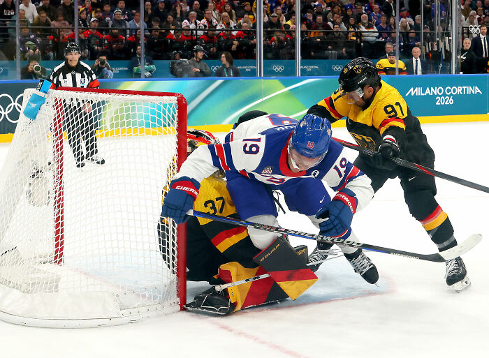 Olympic hockey rivals in action near the goal, capturing a heated rivalry moment during a high-stakes match.
