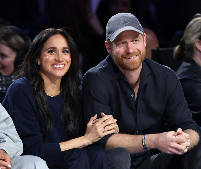 Prince Harry and Meghan Markle sitting close together, smiling at NBA All-Star Game, showcasing body language. Prince Harry and Meghan Markle sitting close together, smiling at NBA All-Star Game, showcasing body language.