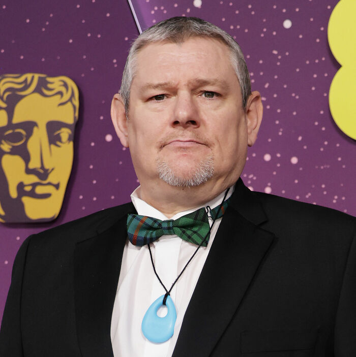 Man in a black suit and green bow tie at BAFTA event, symbolizing Michael B. Jordan's reaction to audience incident revealed.