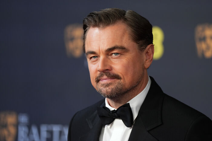 Leonardo DiCaprio in a black tuxedo at a formal event, symbolizing Heat 2 and the DC showdown anticipation.