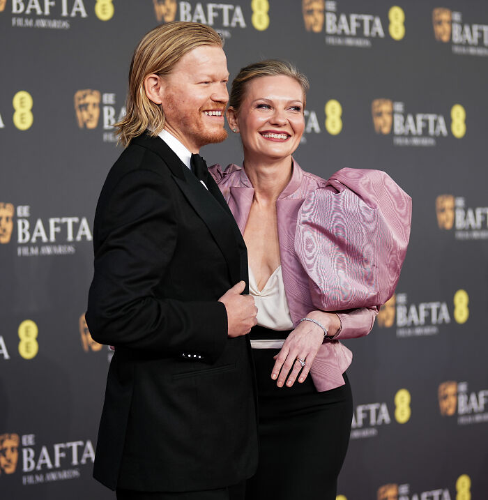 Kirsten Dunst at the BAFTA afterparty smiling in a pink outfit featuring a dramatic puffed sleeve fashion blunder.