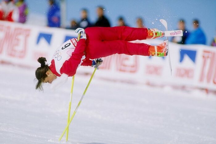 Female Olympic skier performing an aerial trick during a winter competition showcasing unhinged Olympic sports madness.