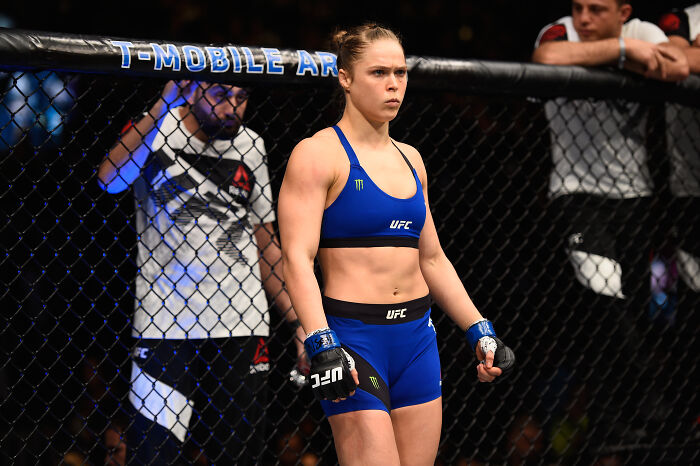 Ronda Rousey inside UFC octagon wearing blue fight gear before a match, focused and ready for competition. Ronda Rousey inside UFC octagon wearing blue fight gear before a match, focused and ready for competition.