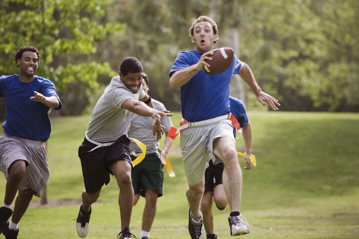 Young men playing a competitive game of flag football outdoors, showcasing dynamic movement in Olympic sports summer matches.
