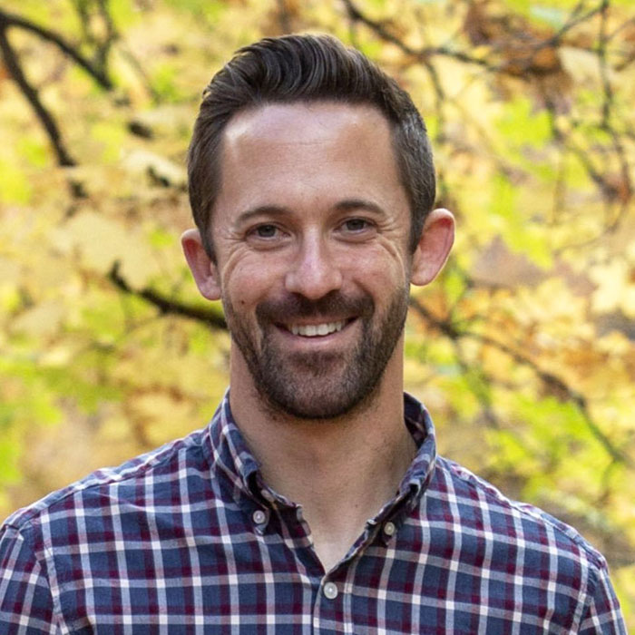 Smiling man in a plaid shirt outdoors with autumn leaves in the background, related to missing kids returned to dad.