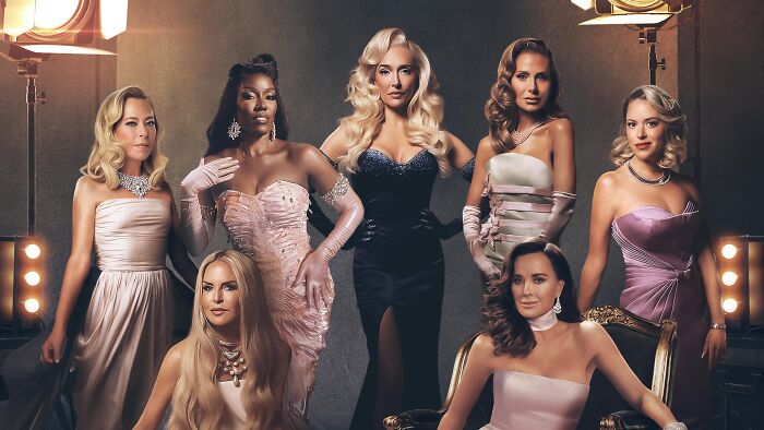 Cast members of The Real Housewives of Beverly Hills dressed elegantly posing in a studio setting with vintage lighting.