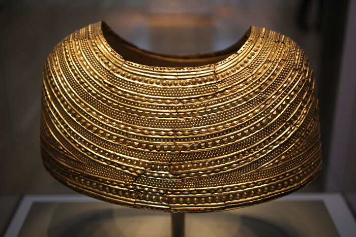 Antique gold collar displayed in a museum, showcasing intricate craftsmanship of almost perfectly preserved historical item.