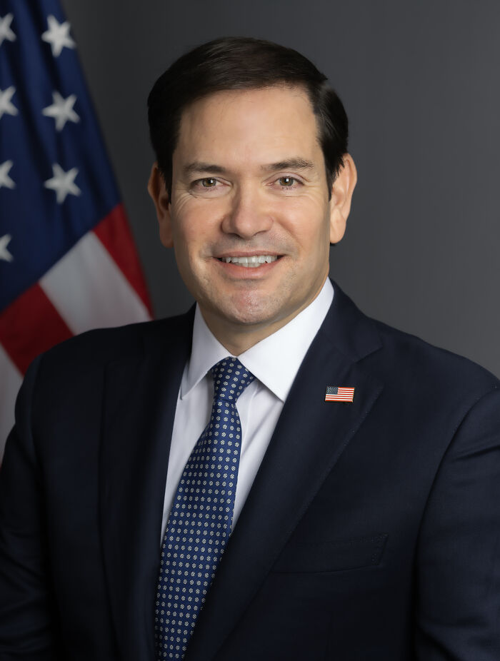 Professional portrait of a man in a suit with an American flag pin, symbolizing the theme of men traumatized by women.