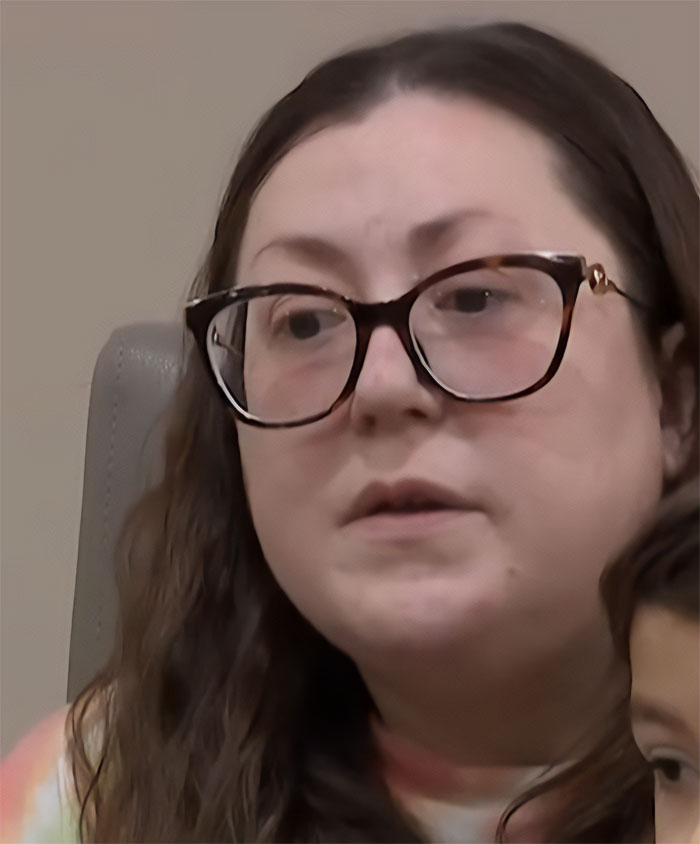 Woman with glasses speaking seriously, discussing severe facial burns from a dangerous TikTok trend involving a 9-year-old.