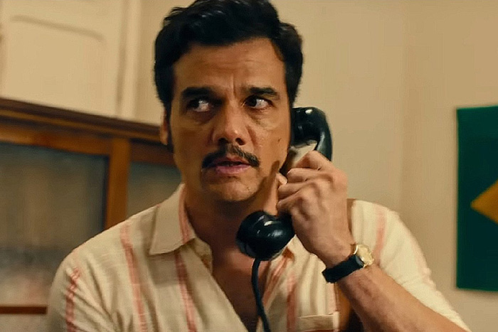 Man with mustache holding a phone, appearing tense, scene from Oscar nominated movies 2026.