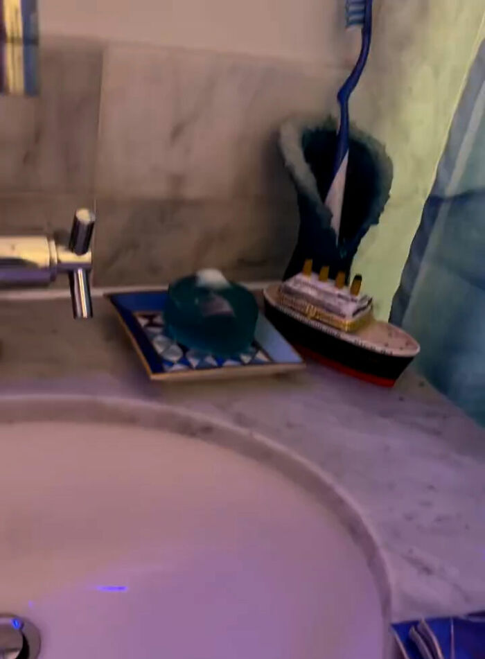 NYC apartment bathroom sink area featuring Titanic movie set model ship and decorative soap dish on countertop. NYC apartment bathroom sink area featuring Titanic movie set model ship and decorative soap dish on countertop.