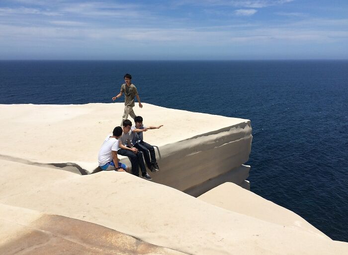 Group of people exploring an unusual place by the ocean with unique white rock formations on a clear day