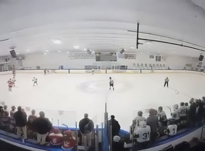 Indoor ice hockey rink with players and spectators during a Rhode Island hockey game before tragedy involving transgender mom Roberta Esposito.