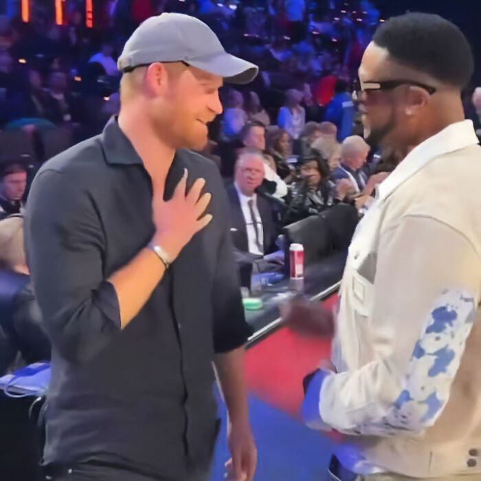 Prince Harry at NBA All-Star Game, smiling and touching chest, engaging in conversation, body language analyzed. Prince Harry at NBA All-Star Game, smiling and touching chest, engaging in conversation, body language analyzed.