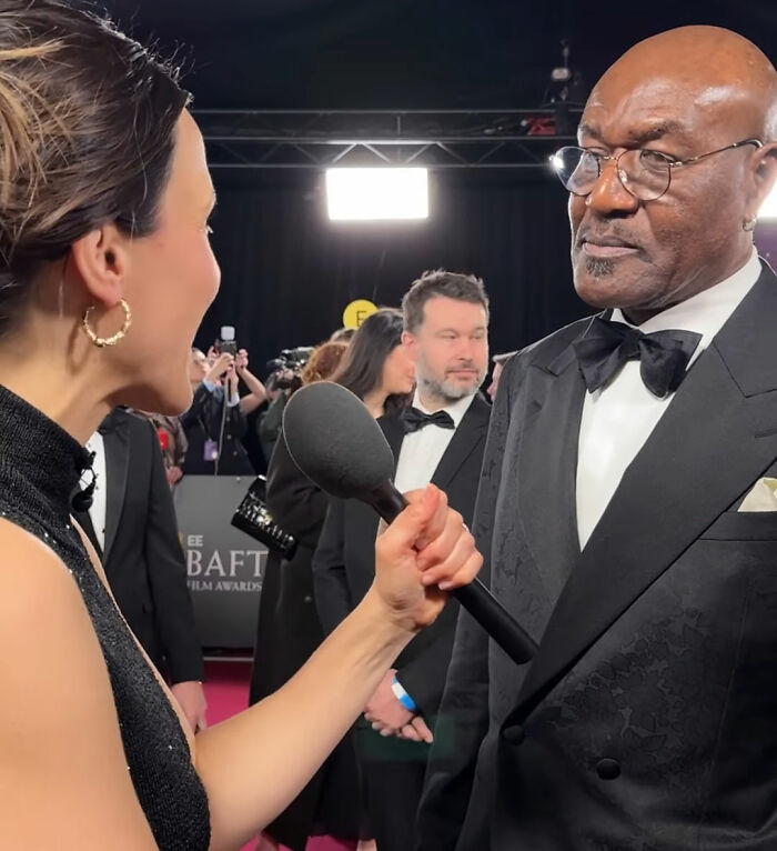 Interviewer speaking to a man in a tuxedo at the BAFTA event, capturing Michael B. Jordan's reaction moment.