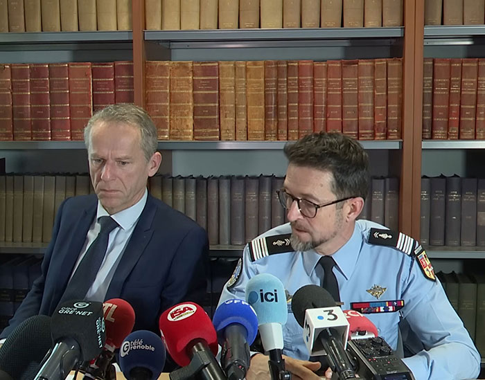 Police official and lawyer speaking at a press conference about teacher accused of crimes against victims