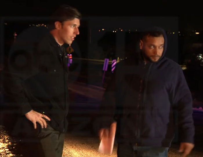 Two men standing outdoors at night, one appearing to speak, related to man detained in Nancy Guthrie kidnapping case.