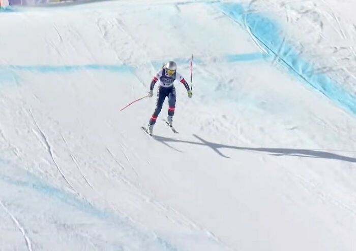 Olympian skiing downhill in full gear on snowy slope amid investigation into broken medals ordered from TEMU.